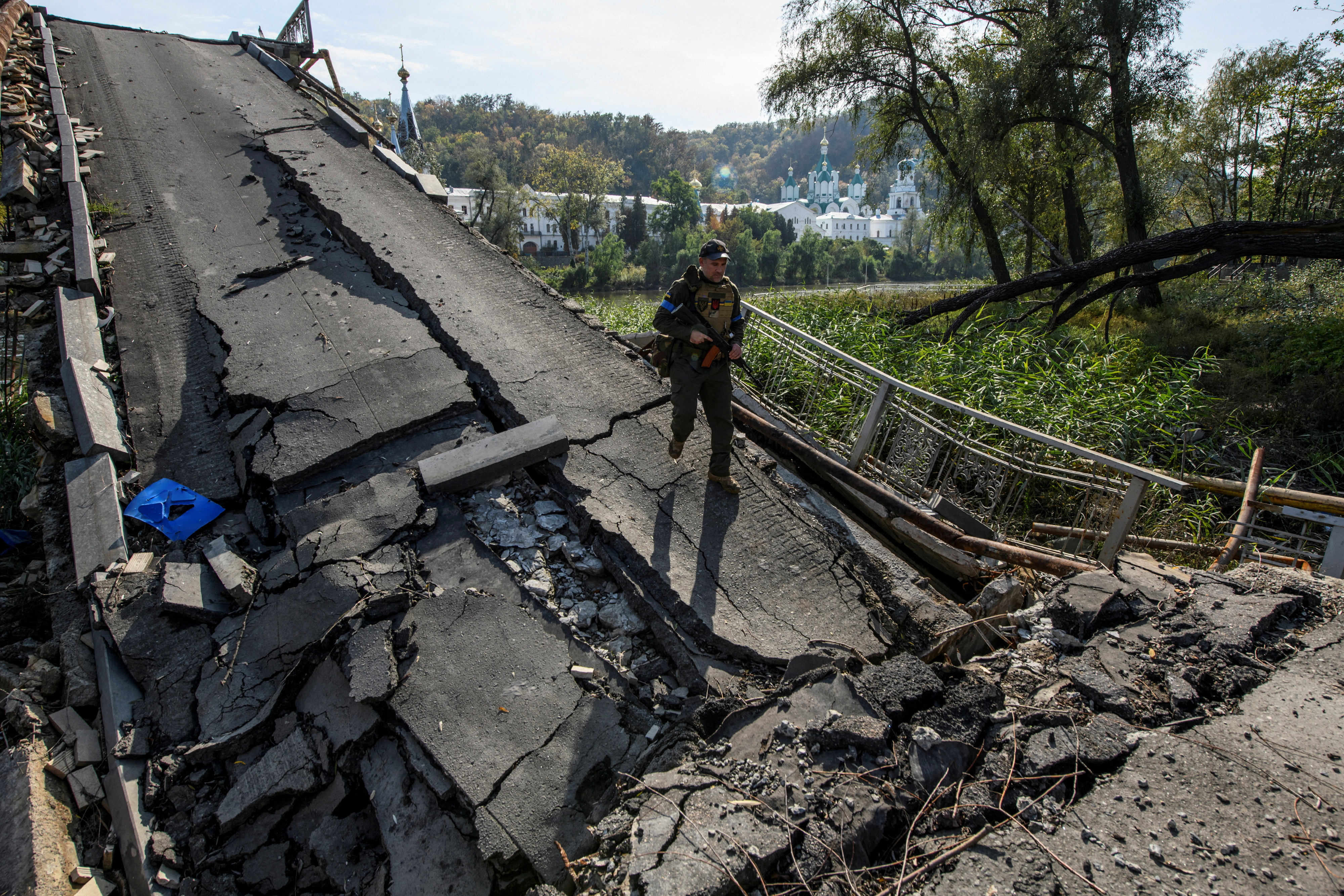 A member of Ukraine's National Guard walks on a bridge over the Siverskyi Donets river destroyed during Russia's attack on Ukraine, in the town of Sviatohirsk. Vladyslav Musiienko / Reuters