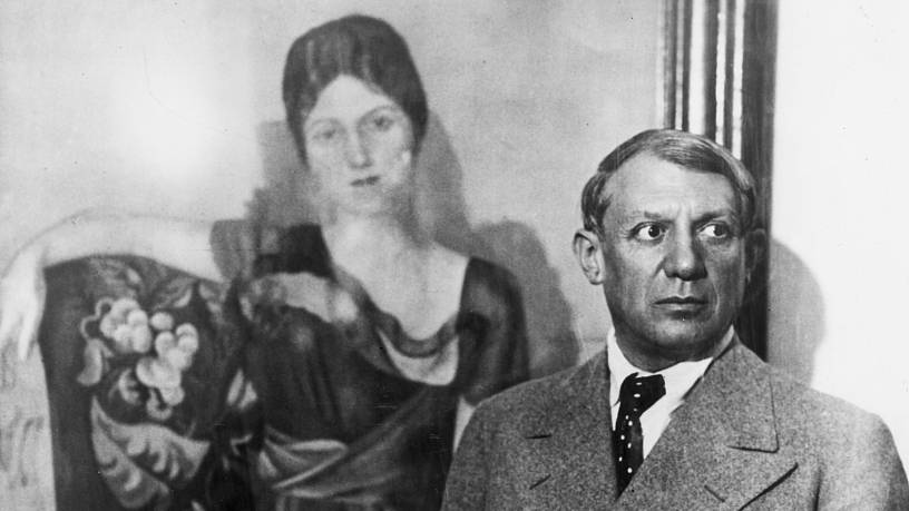 Picasso, in around 1935, standing in front of his 1917 painting of his first wife Olga, Russian ballet dancer Olga Kokhlova. /Hulton Archive/Getty Images 