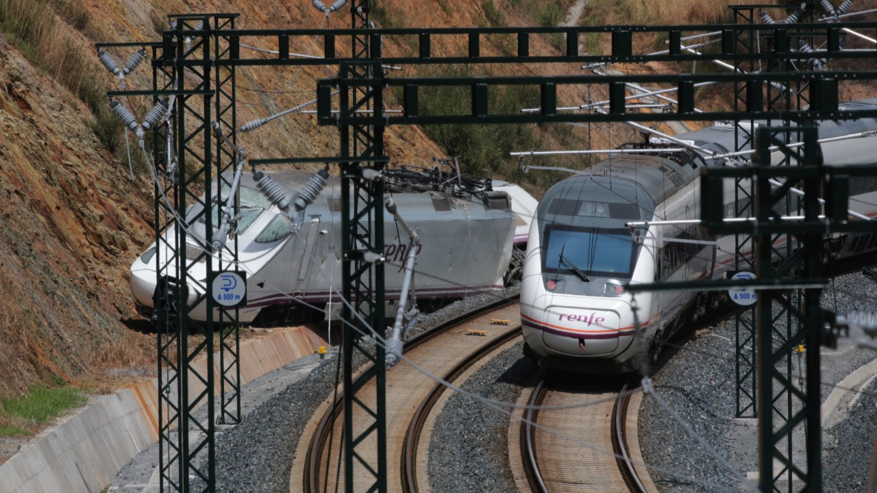 A passenger train passes by a wrecked train engine at the site of a train crash in Santiago de Compostela, northwestern Spain. /Miguel Vidal/File Photo/Reuters