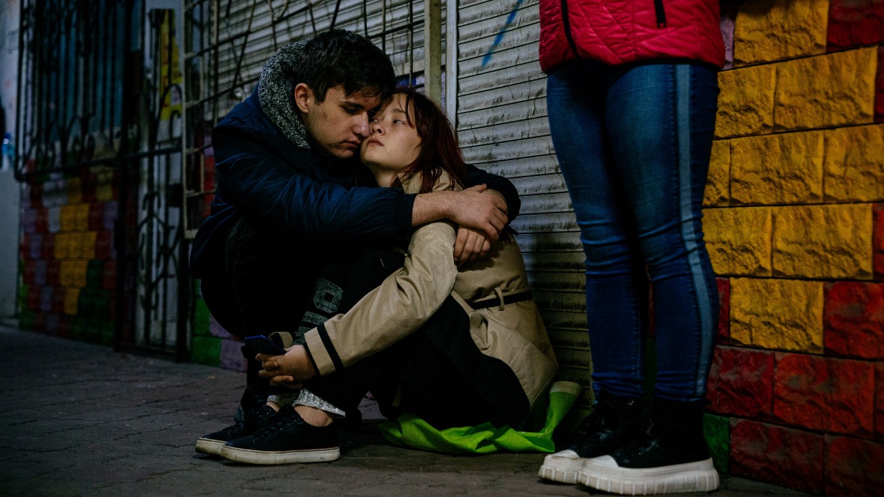 A young couple hugs while hiding in an underground crosswalk during an air alert in Zaporizhzhia. /Dimitar Dilkoff/AFP