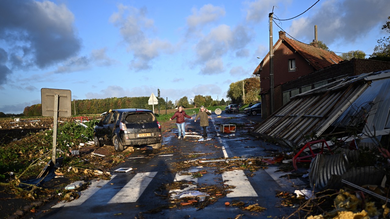 Local residents walk past damages in Bihucourt, northern France, after a tornado hit the region. /Sameer Al-Doumy/AFP