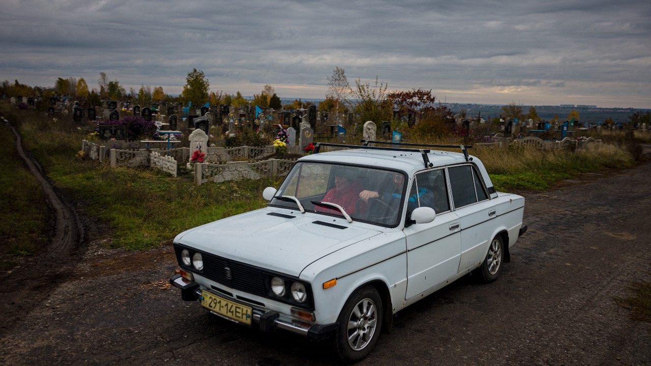 Local residents ride a car through a cemetery after a visit in the town of Bakhmut, in eastern Ukraine's Donbas region. /Dimitar Dilkoff/AFP