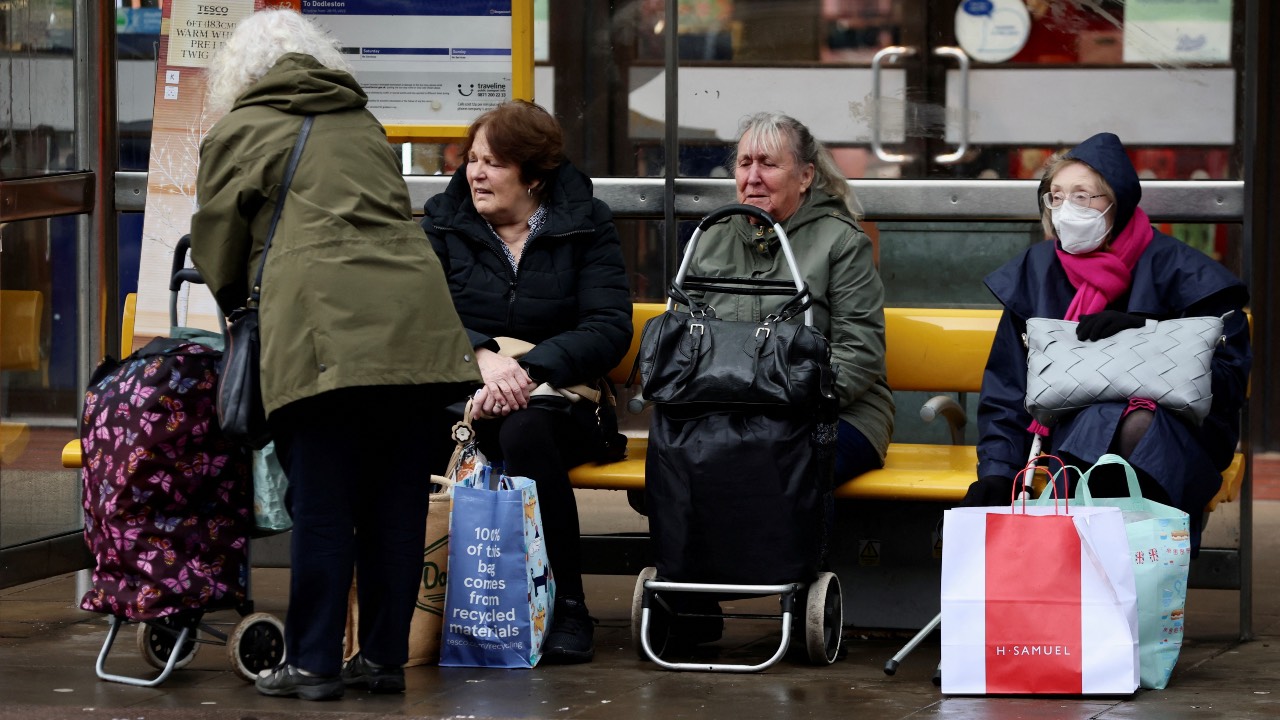 Women sit with shopping trolleys at a bus stop in Chester, England. /Phil Noble/Reuters