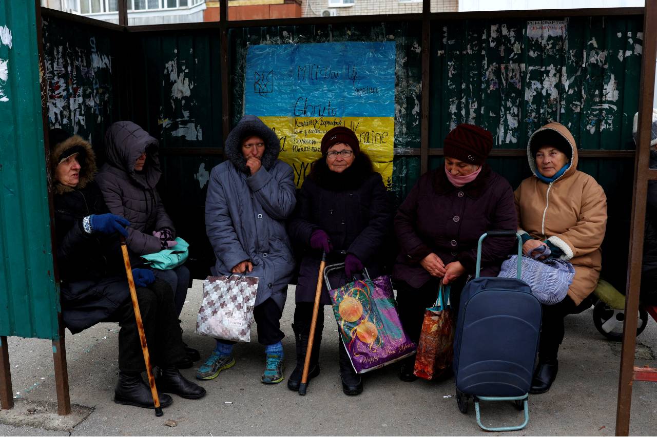 Women pause at a bus stop as they wait for the distribution of humanitarian aid in Kherson. /Murad Sezer/Reuters
