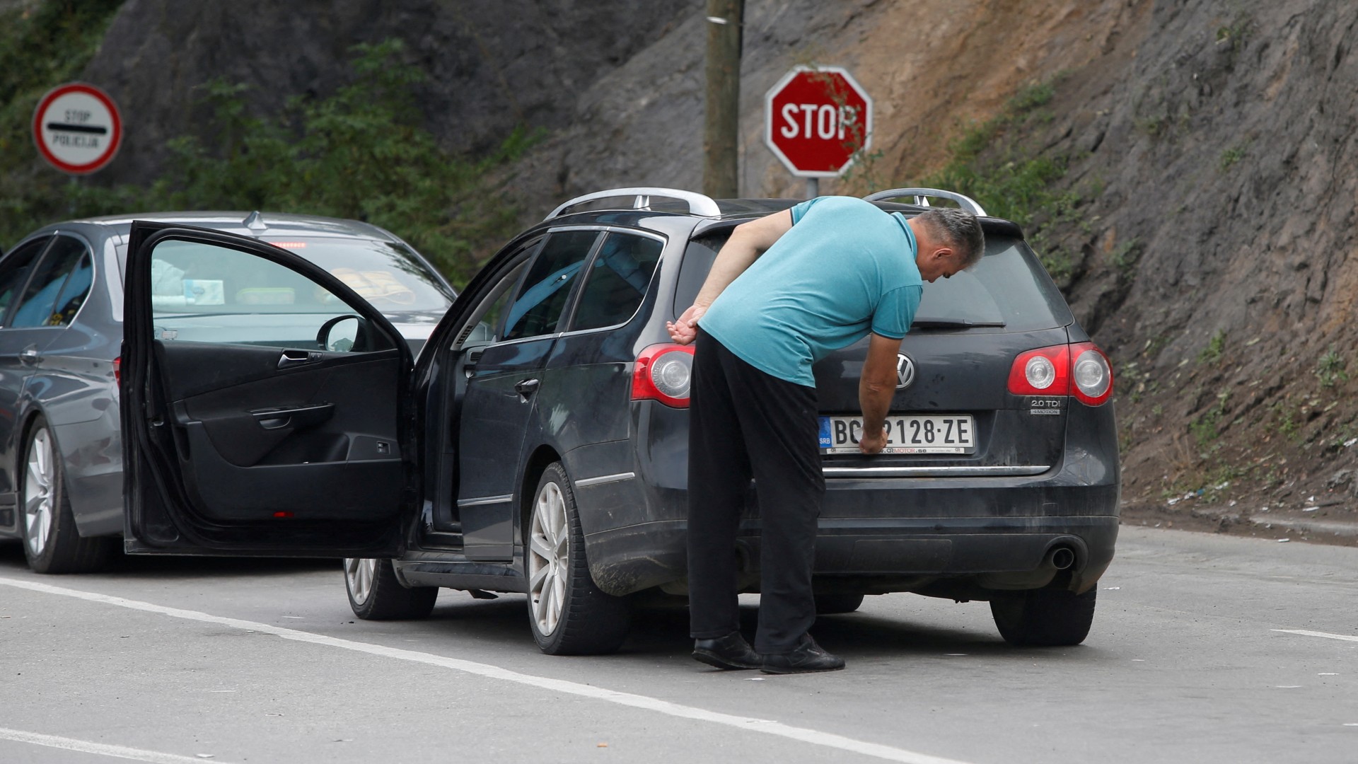 A driver changes the national markings on his car plates at the border crossing between Kosovo and Serbia. /Ognen Teofilovski/Reuters