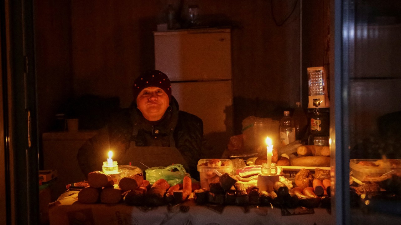 A vendor waits for customers in a small store that is lit with candles during a power outage after critical civil infrastructure was hit by Russian missile attacks, in Odesa, Ukraine. /Serhii Smolientsev/Reuters