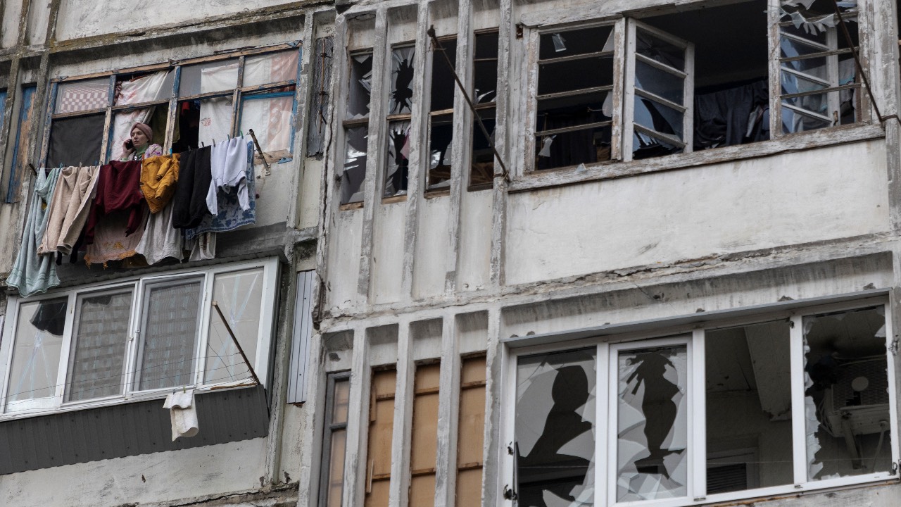 A local woman speaks on her mobile phone in a window of a residential building damaged by a Russian military strike in Kherson, Ukraine. /Anna Voitenko/File photo/Reuters