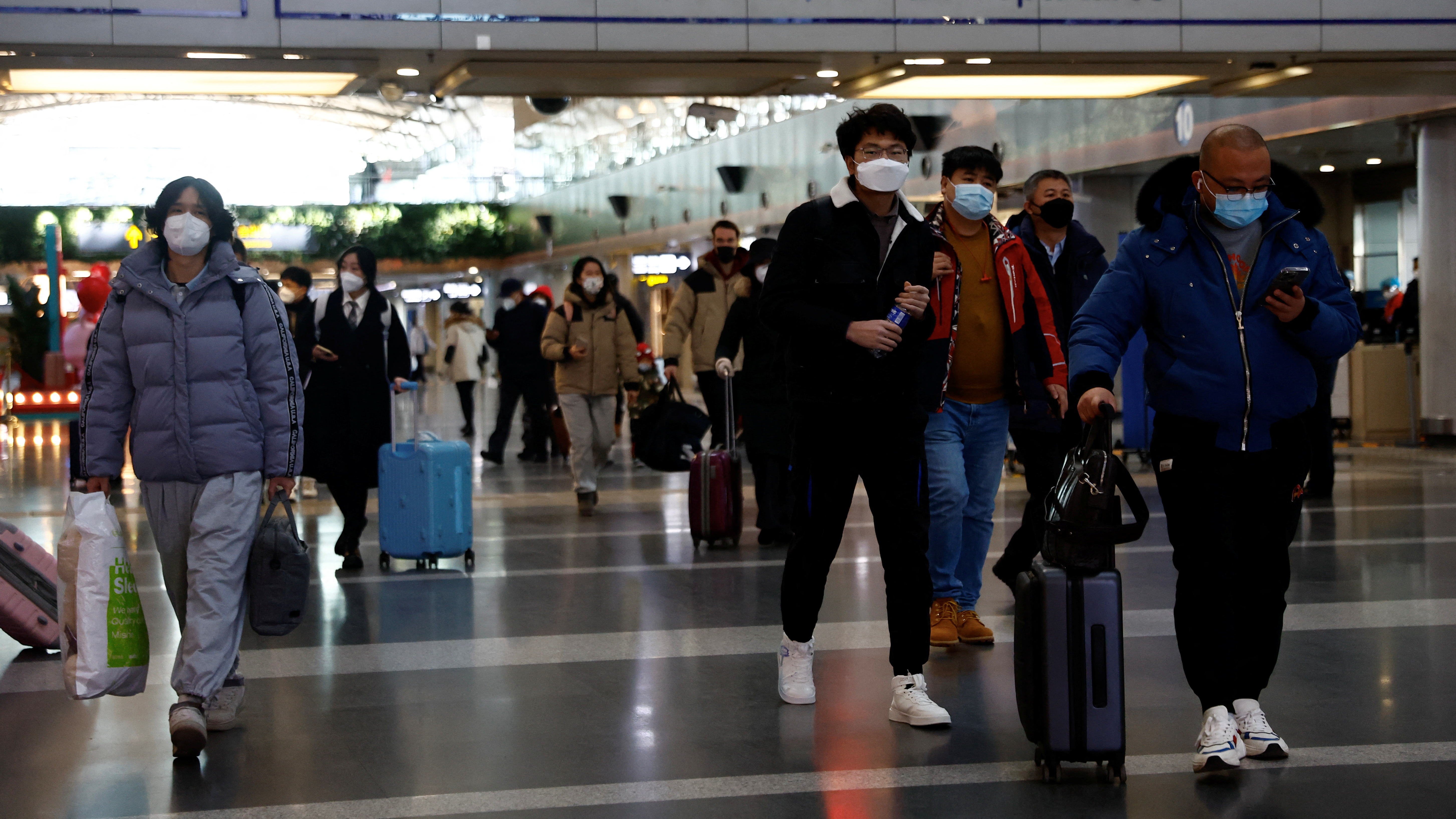 Travellers walk with their luggage at Beijing Capital International Airport. /Tingshu Wang/Reuters