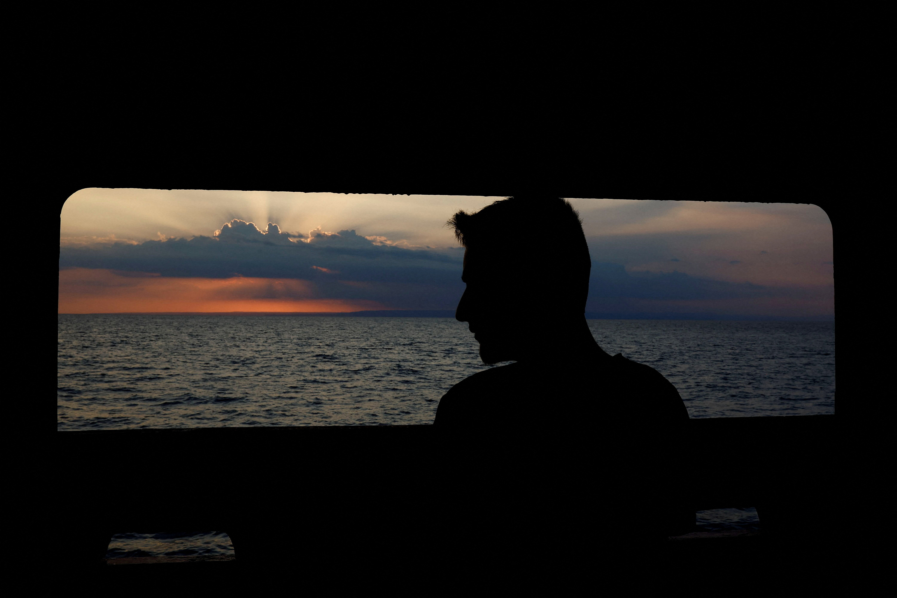 A migrant watches the sunshine over Sicily on the ninth day aboard the Open Arms Uno rescue boat, waiting for the Italian government to give them a port to disembark. /Juan Medina/Reuters