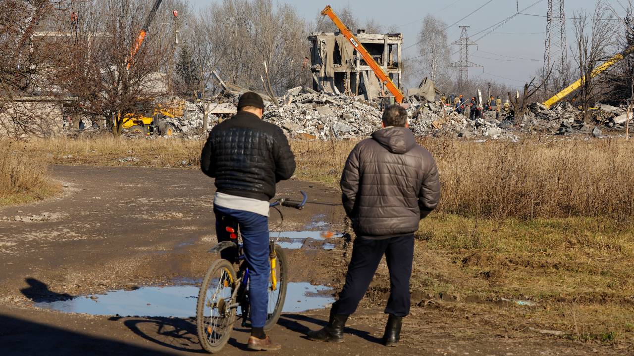 Men watch workers removing debris from the attack in Makiivka on Tuesday. /Alexander Ermochenko/Reuters