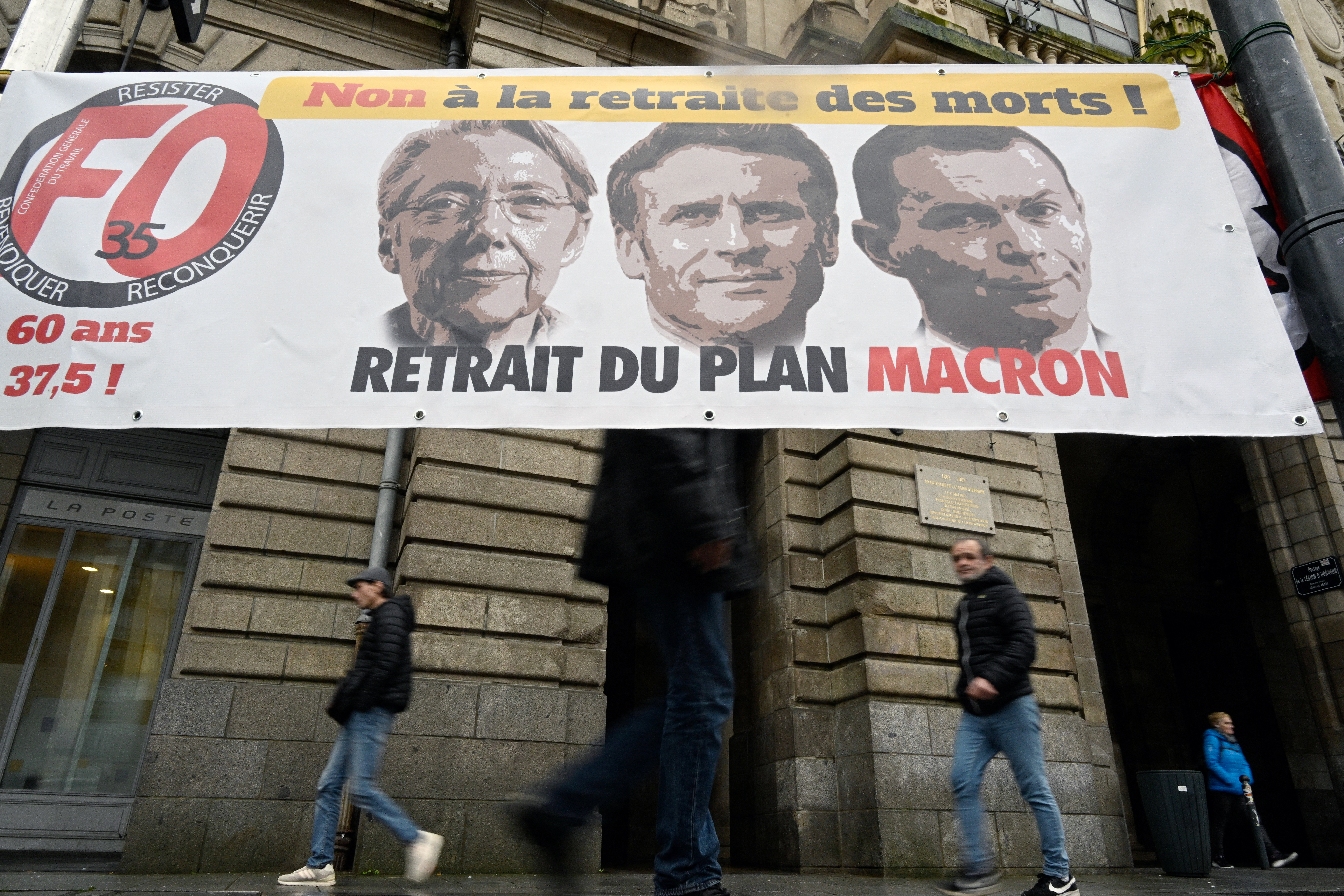 A protest banner in Rennes bearing portraits of Prime Minister Elisabeth Borne, President Emmanuel Macron and Labor Minister Olivier Dussopt, reads 'no pension for the dead people.'  /Damien Meyer/AFP