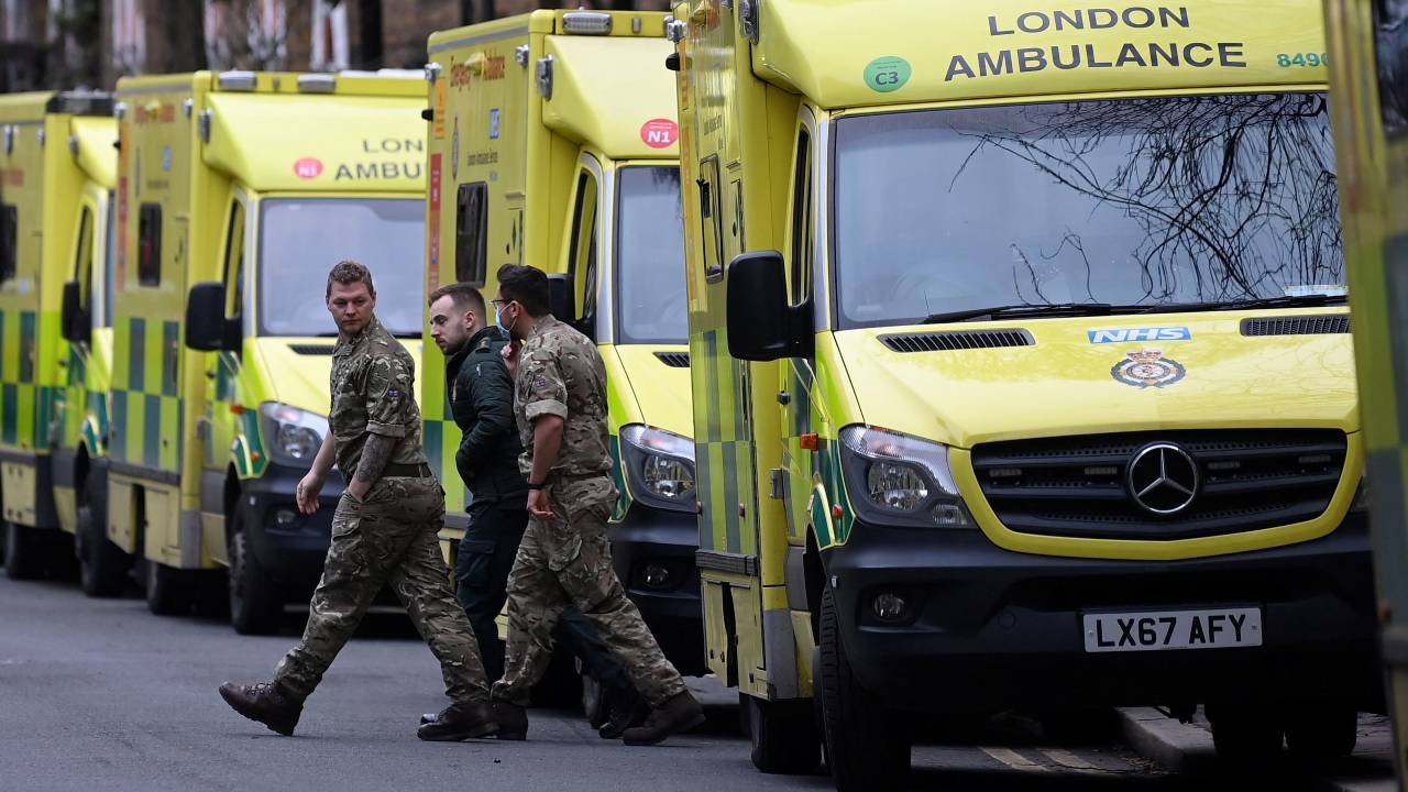 Military personnel and an ambulance worker walk between an ambulance amid a strike by ambulance workers. /Toby Melville/Reuters