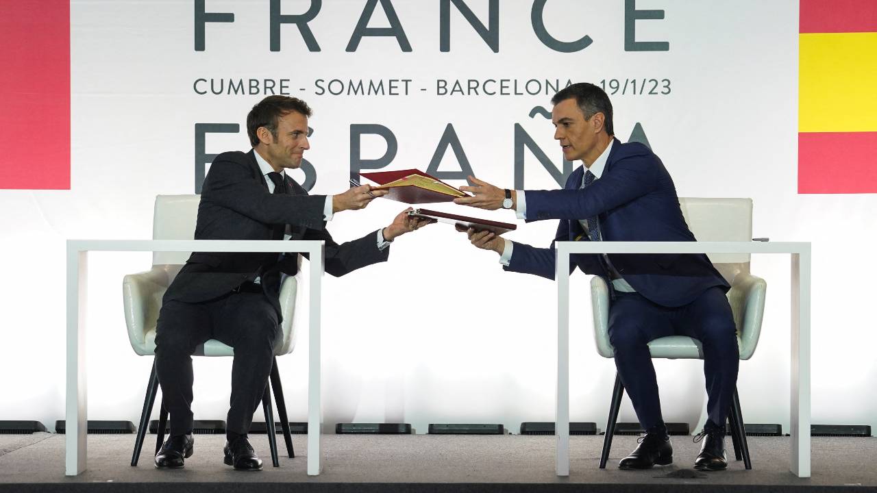Spain's Prime Minister Pedro Sanchez and French President Emmanuel Macron pass each other documents during the signing ceremony. /Bruna Casas/Reuters