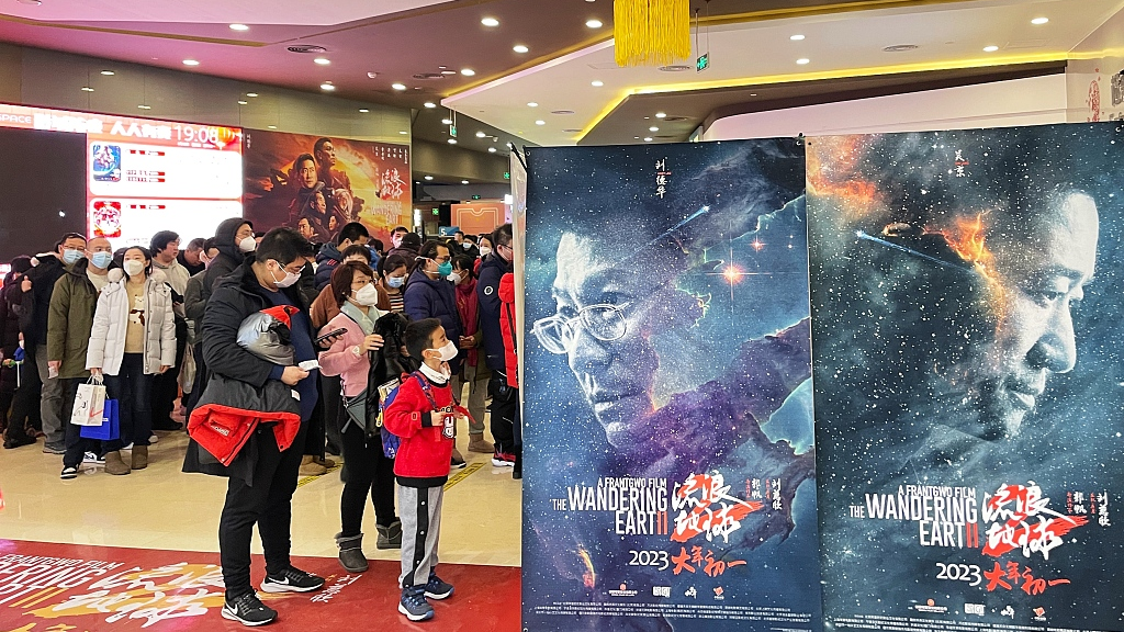 Moviegoers queue at a cinema in Beijing, in front of two posters advertising 'The Wandering Earth II'. /CFP.CN/