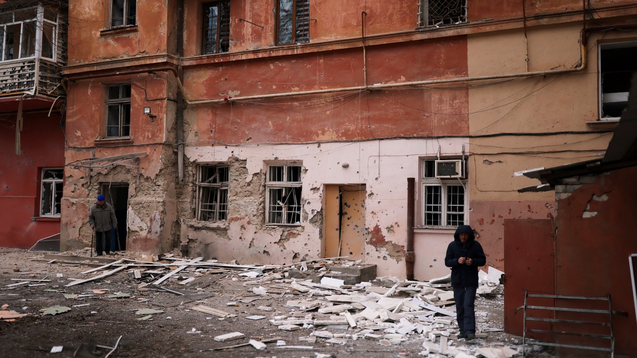 Residents walk in front of their apartment building damaged by a Russian military strike in Kherson. /Nacho Doce/Reuters