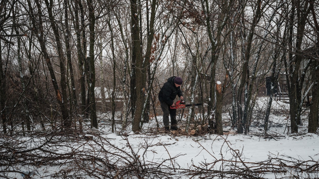 A man uses a chain saw to cut down trees for wood in Bakhmut, in the Donetsk region. /Yasuyoshi Chiba/AFP
