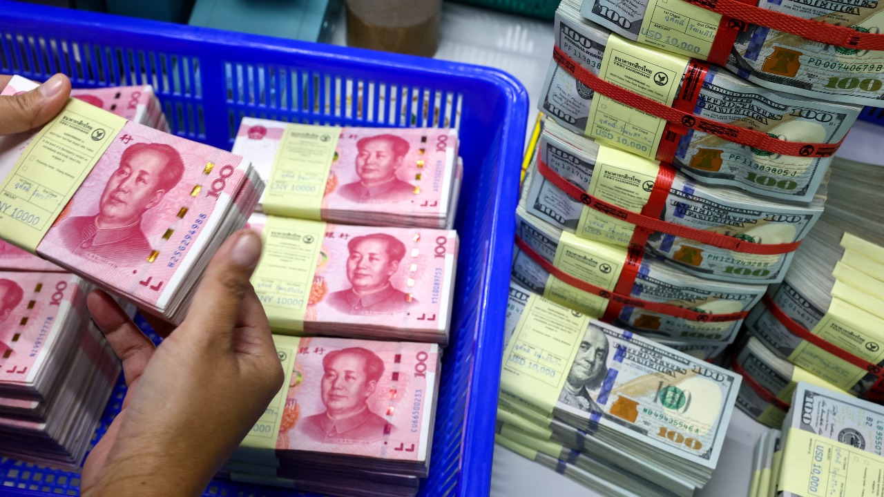 A bank employee count Chinese yuan notes next to U.S. dollar notes at a Kasikornbank in Bangkok, Thailand. /Athit Perawongmetha/Reuters