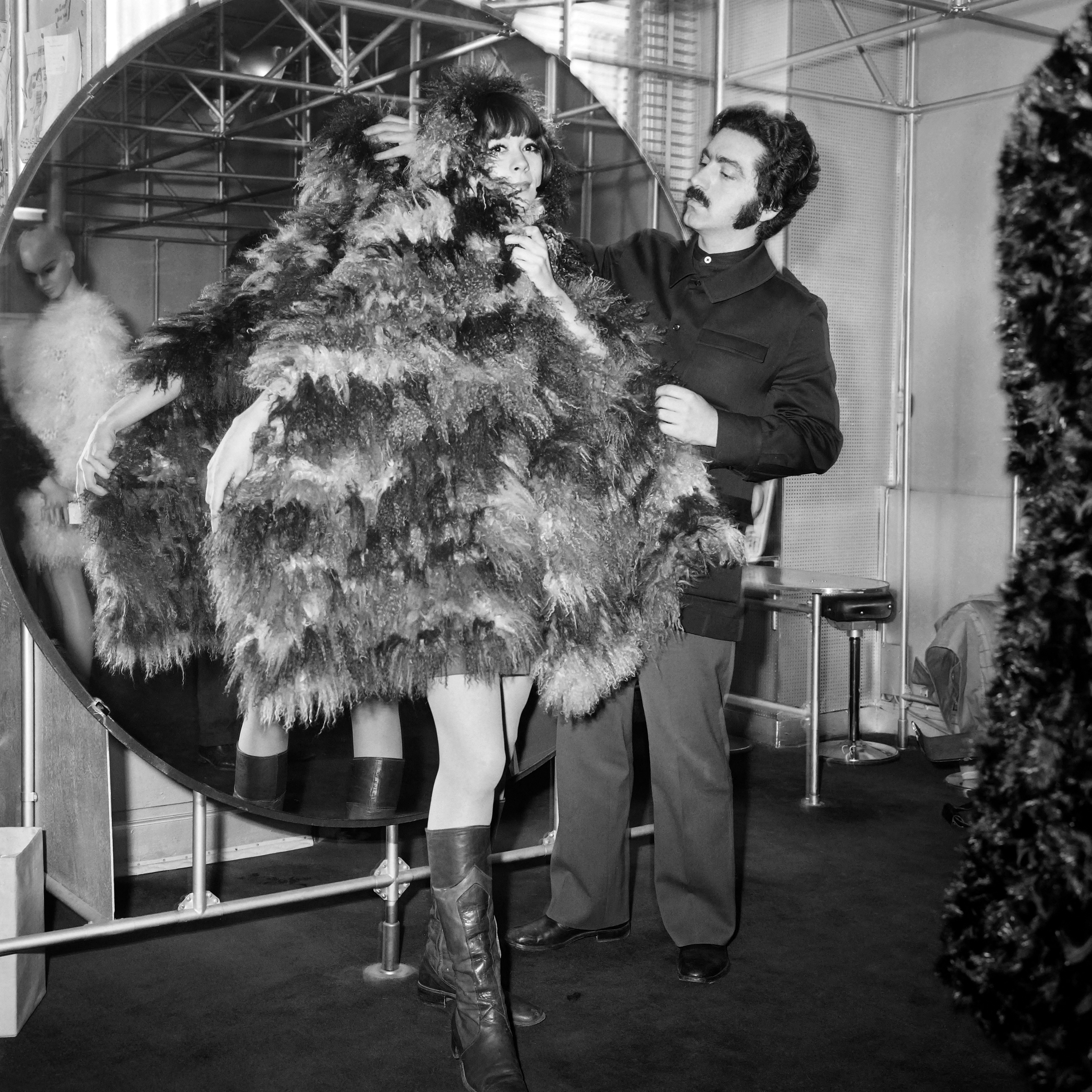 In 1968, Rabanne helps a model as she wears a scarf of Mongoly goat, in his shop in Paris. /AFP
