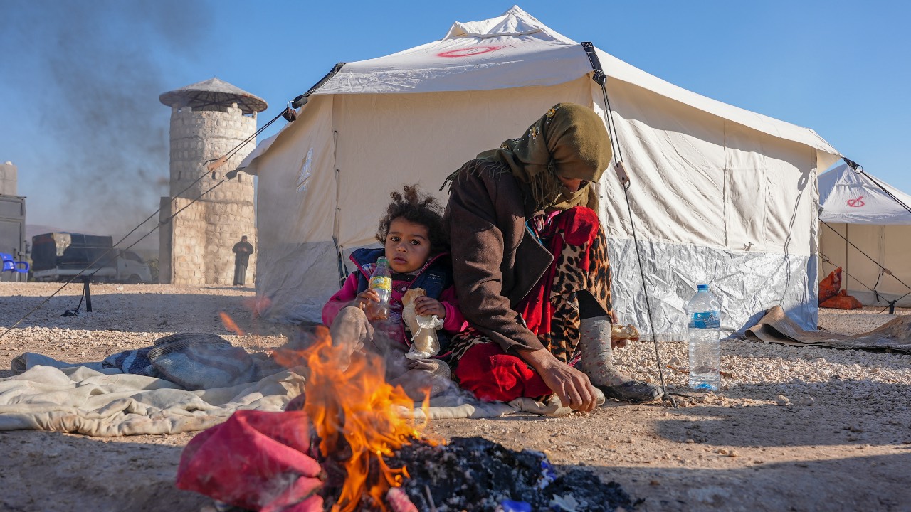 Syrians warm up by a fire at a makeshift shelter for people who were left homeless, near the rebel-held town of Jindayris, after the deadly earthquake. /Rami Al Sayed/AFP