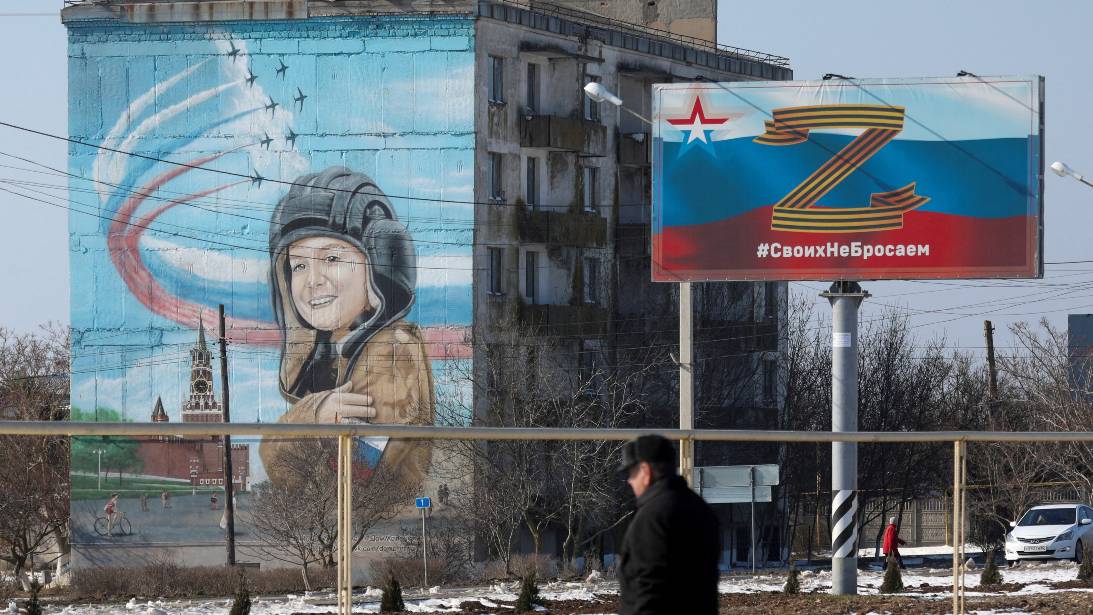 A pedestrian walks near pro-Russian war posters in Crimea's Chernomorskoye. /Alexey Pavlishak/Reuters