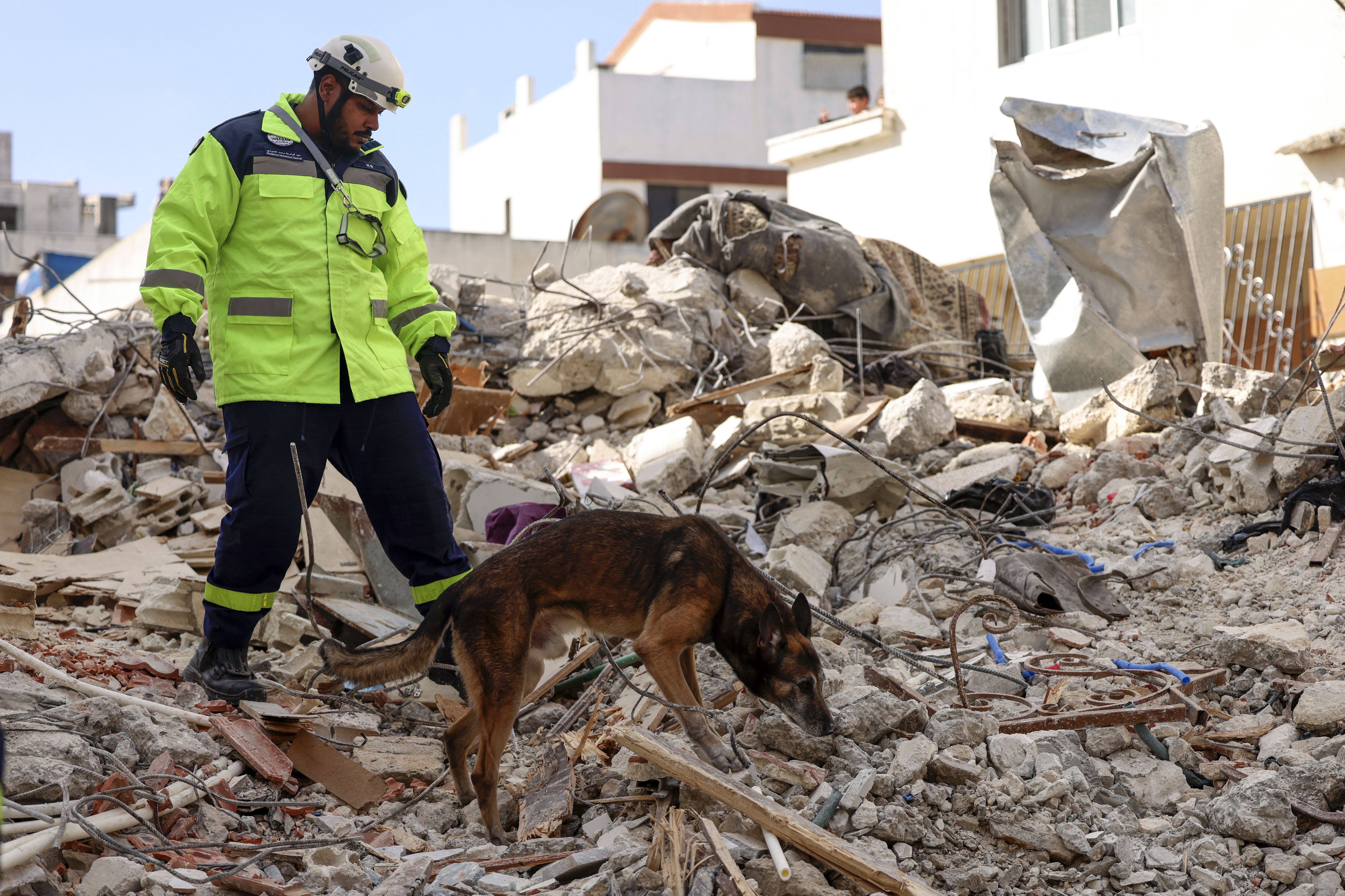 An Emirati rescuer and dog search for victims in the regime-controlled town of Jableh in the province of Latakia, northwest of the Syrian capital. /Karim Sahib/AFP