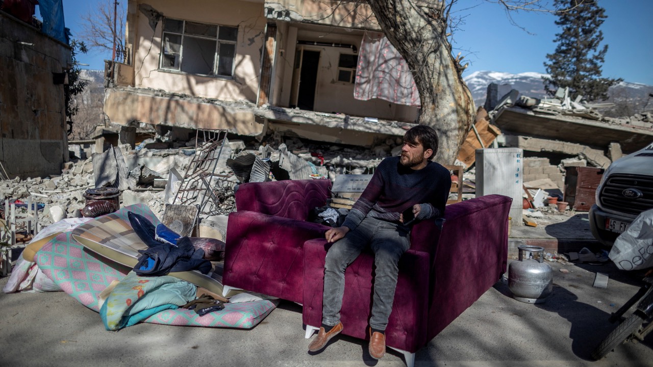 A young man sits outside his destroyed home following the deadly earthquake in Kahramanmaras, Türkiye. /Eloisa Lopez/Reuters