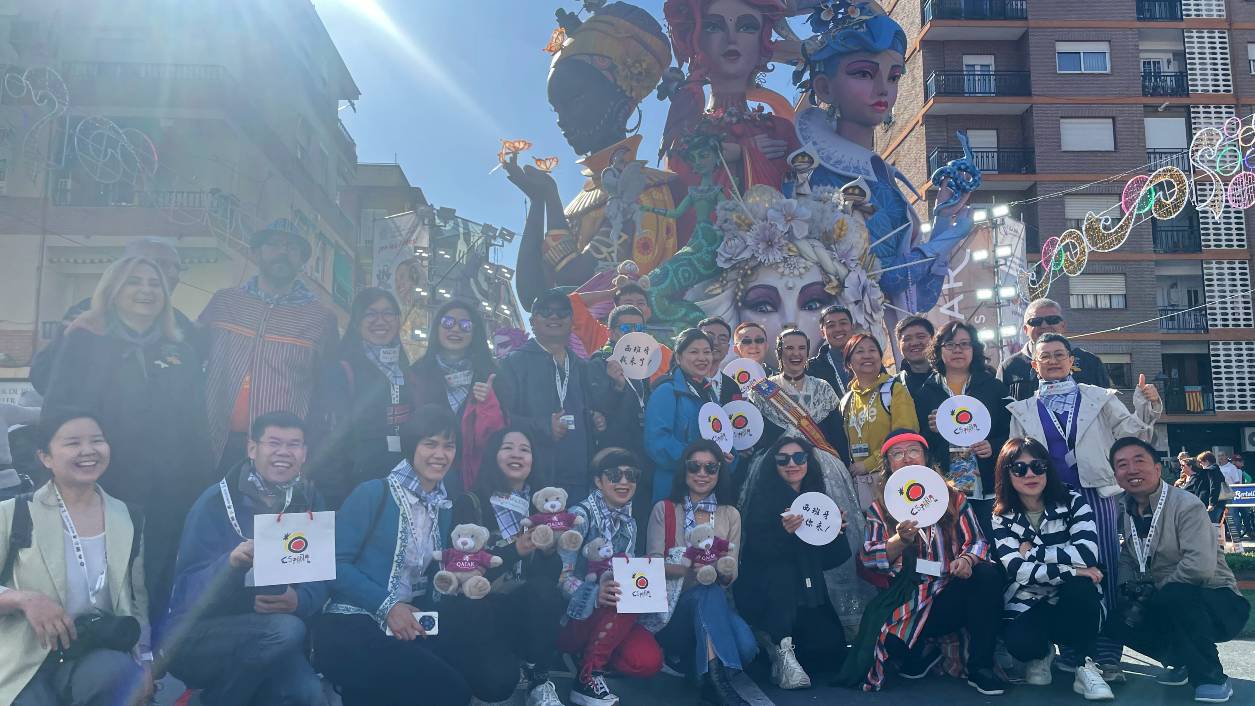 A group of Chinese tour operators, journalists and influencers hold 'Visit Espana' signs in front of a huge falla. /CGTN Europe