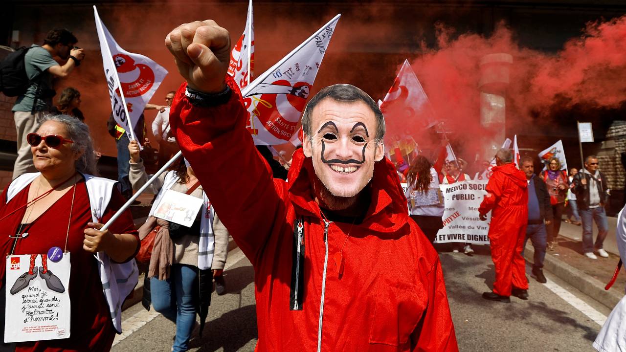 A protester wearing a mask depicting French President Emmanuel Macron in Nice on March 23. /Eric Gaillard/Reuters