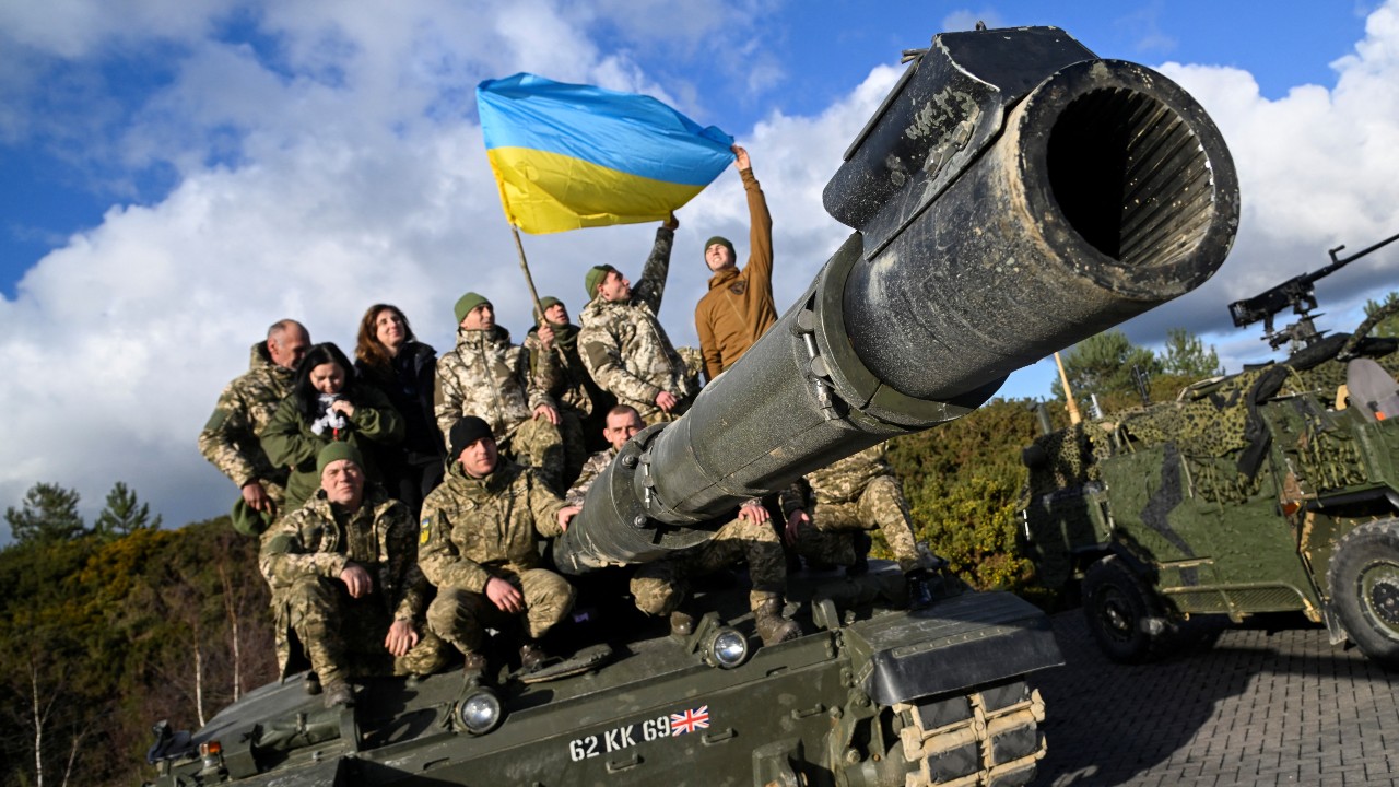 Ukrainian personnel pose with a flag atop a British Challenger 2 tank, which fires munitions incorporating depleted uranium. /Toby Melville/Reuters