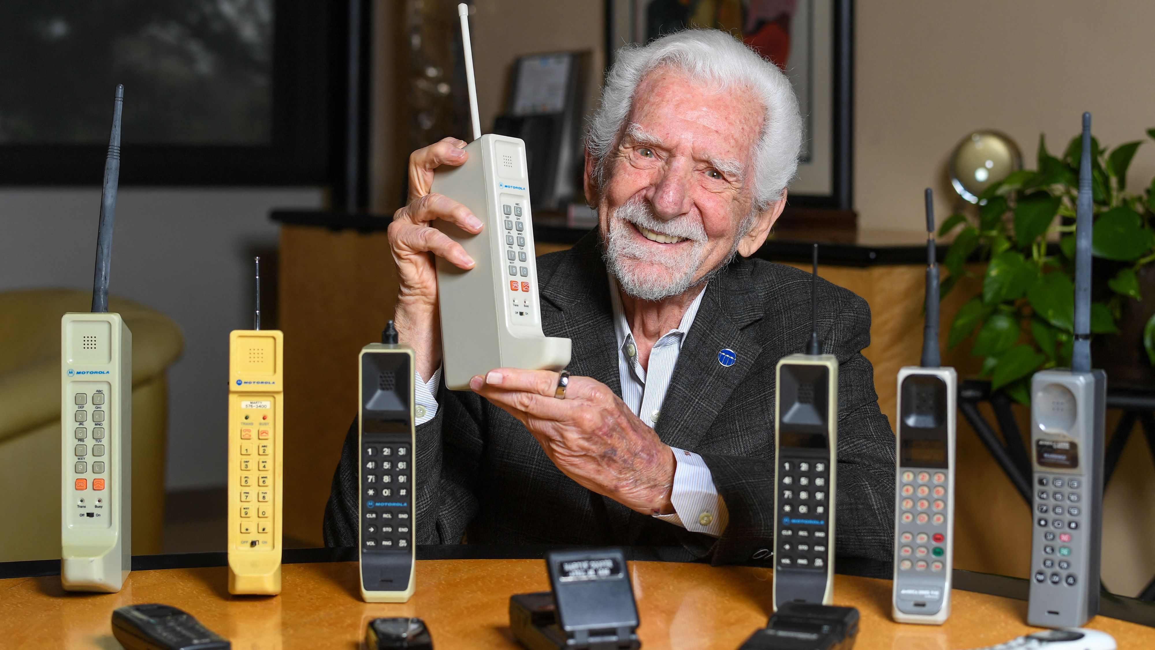 Engineer Martin Cooper holds a copy of the mobile phone he used to make the first cell call to his competitor 50 years ago. /Valerie Macon/AFP