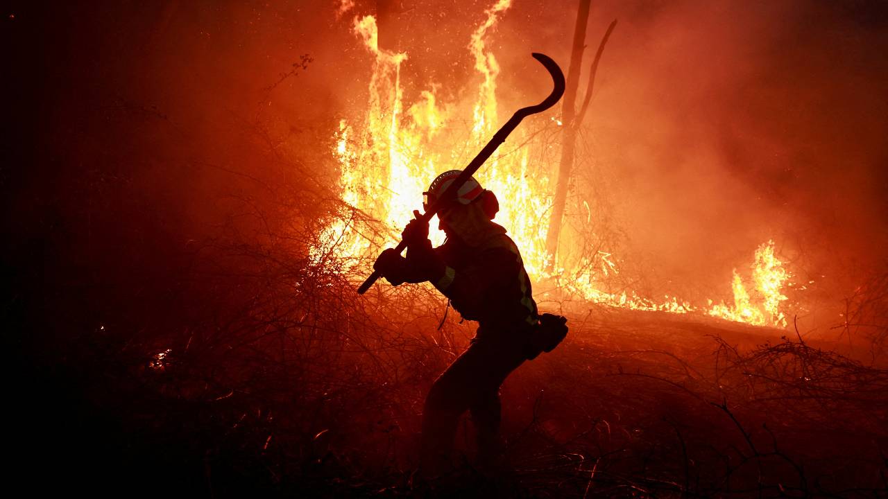 A Galician firefighter tackles flames in a forest during an outbreak of wildfires following a prolonged period of drought and unusually high temperatures in Spain's Asturias. /Vincent West/Reuters