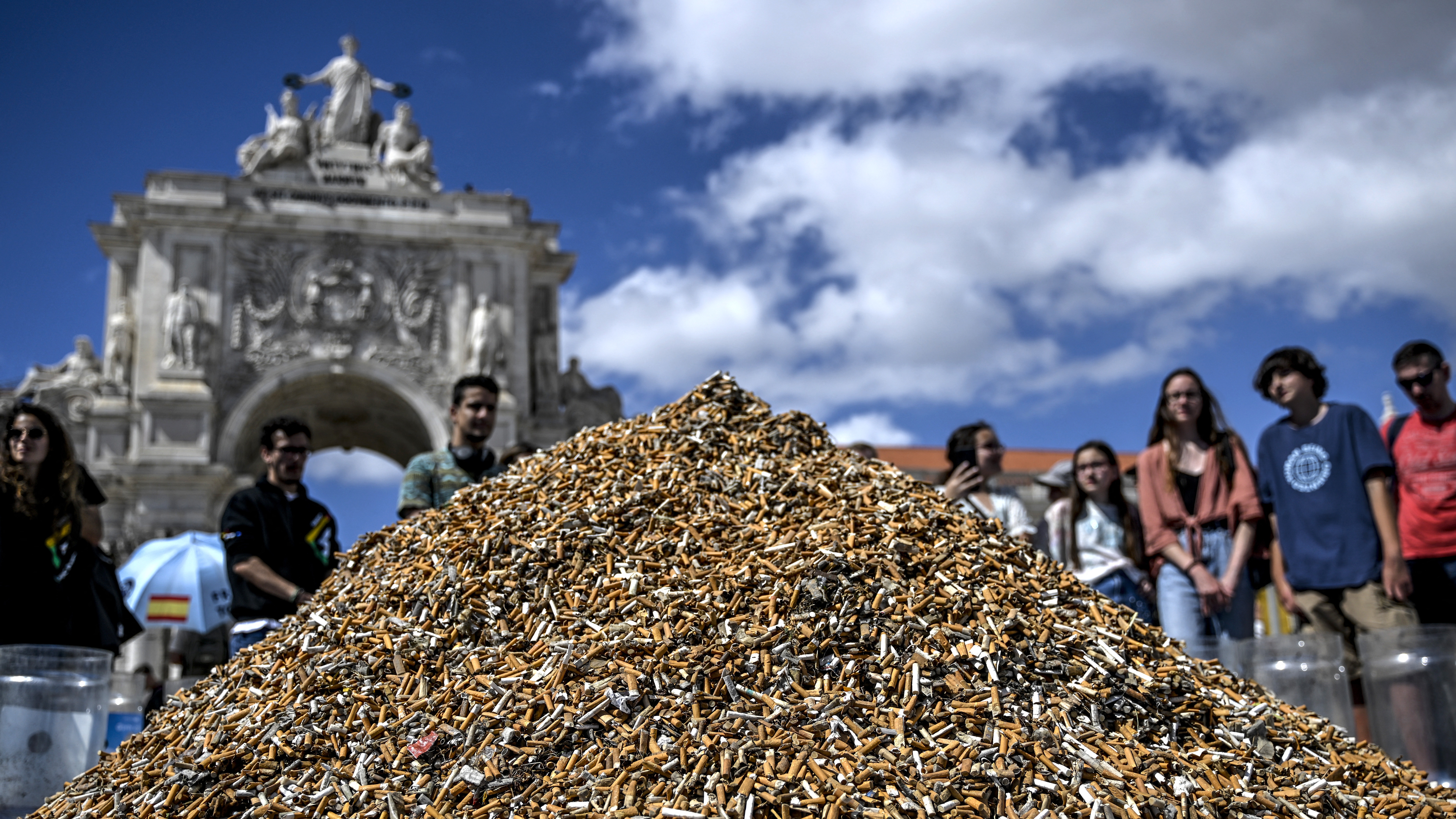Onlookers gaze at a pile of cigarette butts, collected in one week, at Lisbon's Comercio square. /Patricia de Melo Moreira/AFP