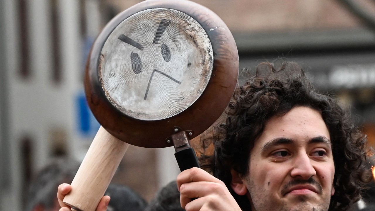 Railing against President Macron, a demonstrator in Strasbourg continues the centuries-old tradition of protesting by banging on kitchen pots and pans. /Frederick Florin/AFP
