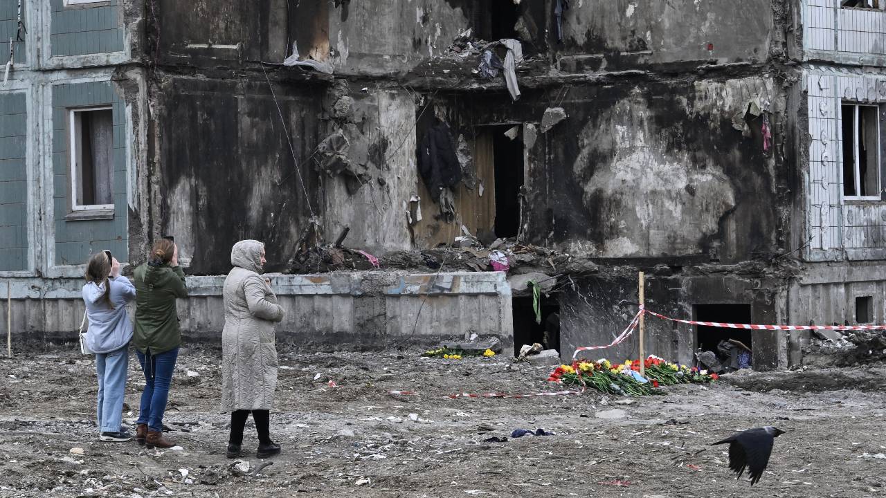 People pay their respects in front of a damaged multistory residential building, where a Russian strike killed 23 people in Uman. /Genya Savilov/AFP