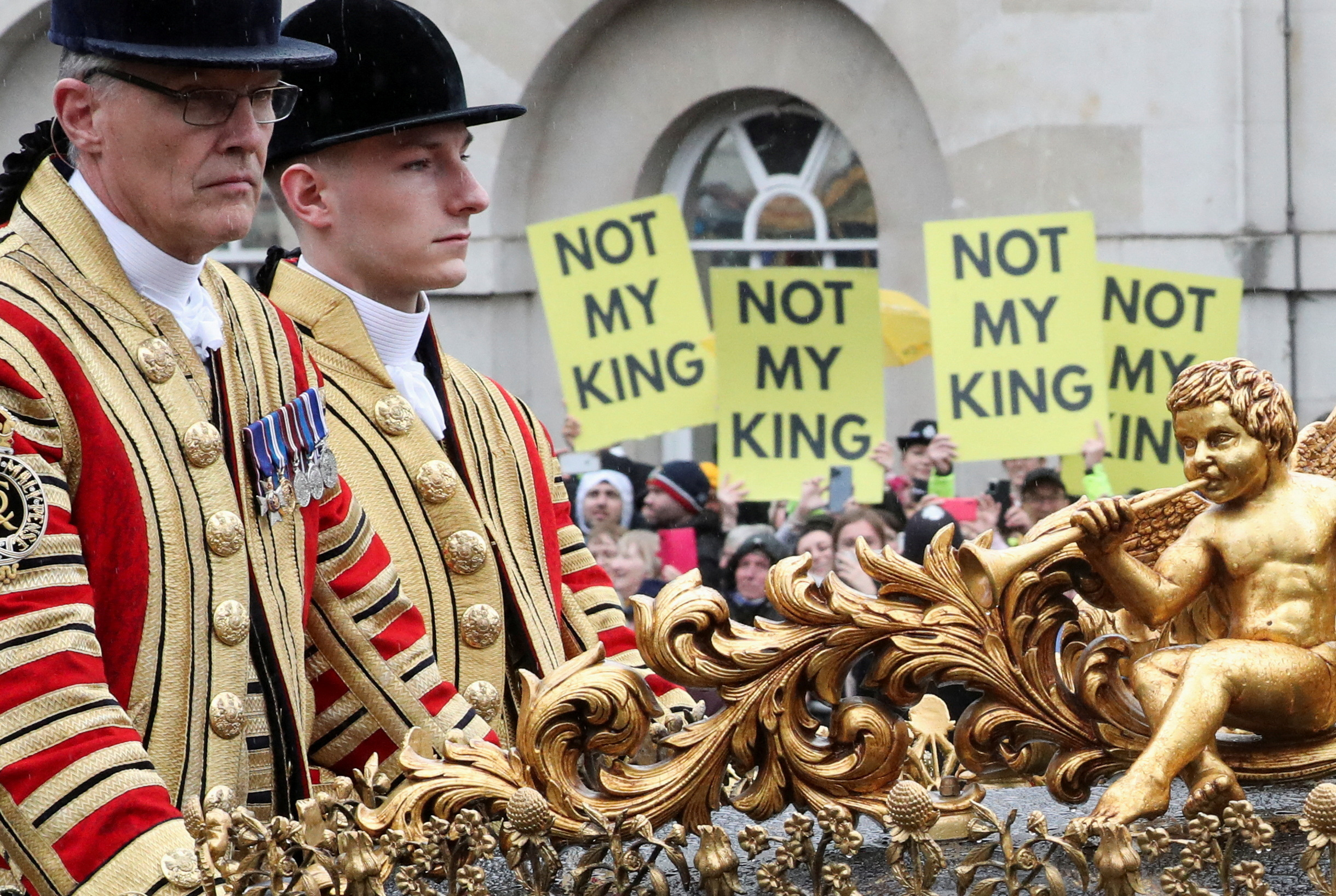 A coach carrying Prince William and Kate at the Coronation rides past protesters. /Violeta Santos Moura/Reuters