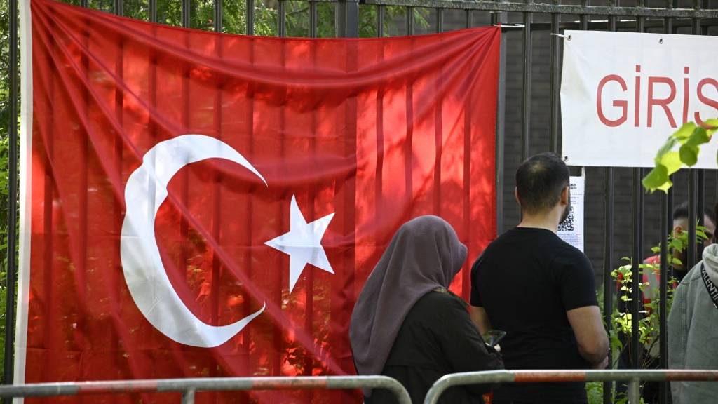 Turkish voters pass a Turkish flag as they make their way to the polling station at the Turkish consulate in Berlin. /Tobias Schwarz/AFP