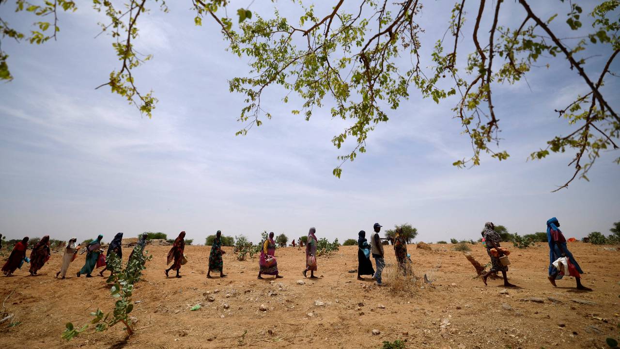 Sudanese refugees fleeing violence walk in line to receive food rations from World Food Programme near the Chad border. /Zohra Bensemra/Reuters