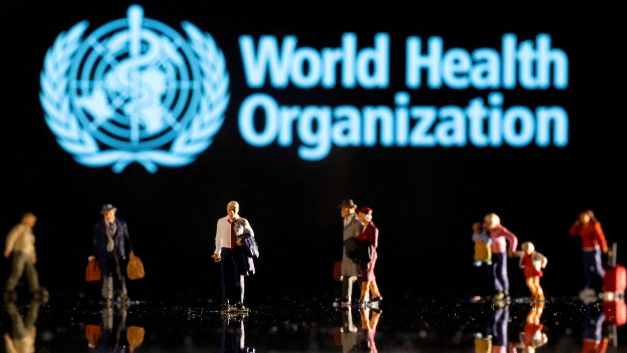 Small figurines are seen in front of displayed World Health Organization logo in this illustration. /Dado Ruvic /Ilustration/Reuters