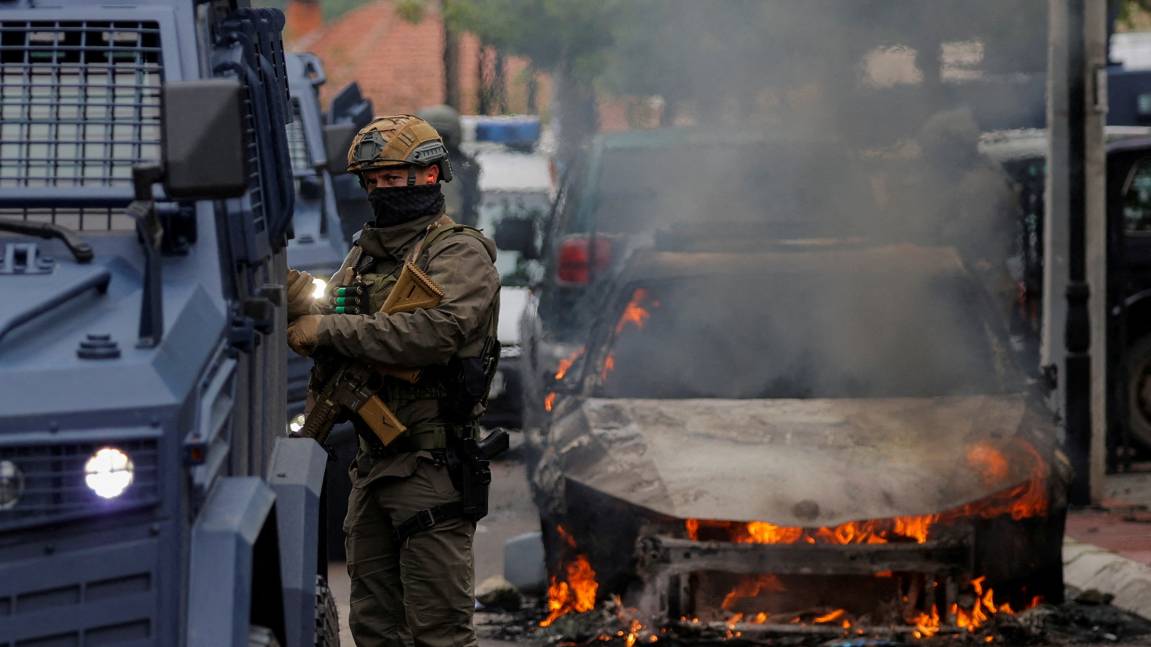 A special police forces officer stands next to a burning car following clashes between Kosovo police and ethnic Serb protesters in the Kosovo town of Zvecan. /Valdrin Xhemaj/Reuters