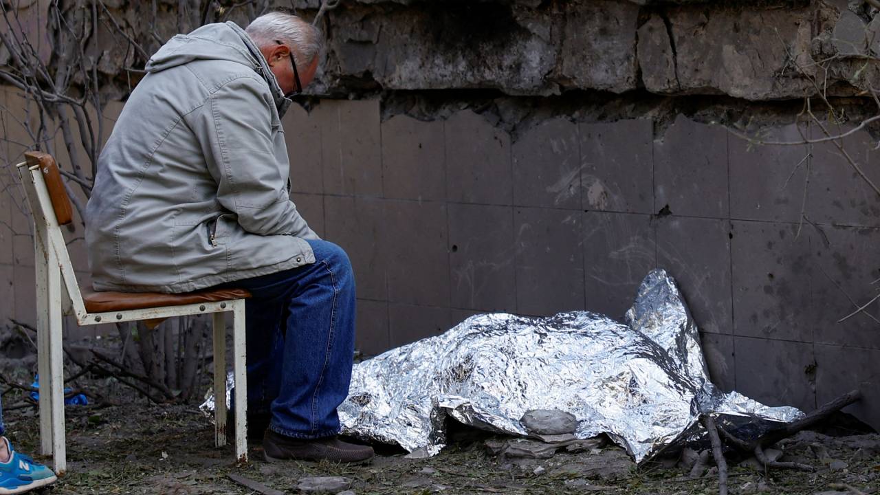 A man sits next to the body of his granddaughter who was killed during a Russian missile strike, in Kyiv./Valentyn Ogirenko/Reuters