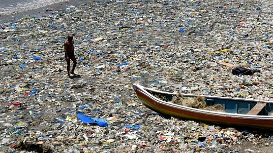 A man walks on the plastic waste borne by the sea in Mumbai, India. /Bhushan Koyande /HT Photo via CFP
