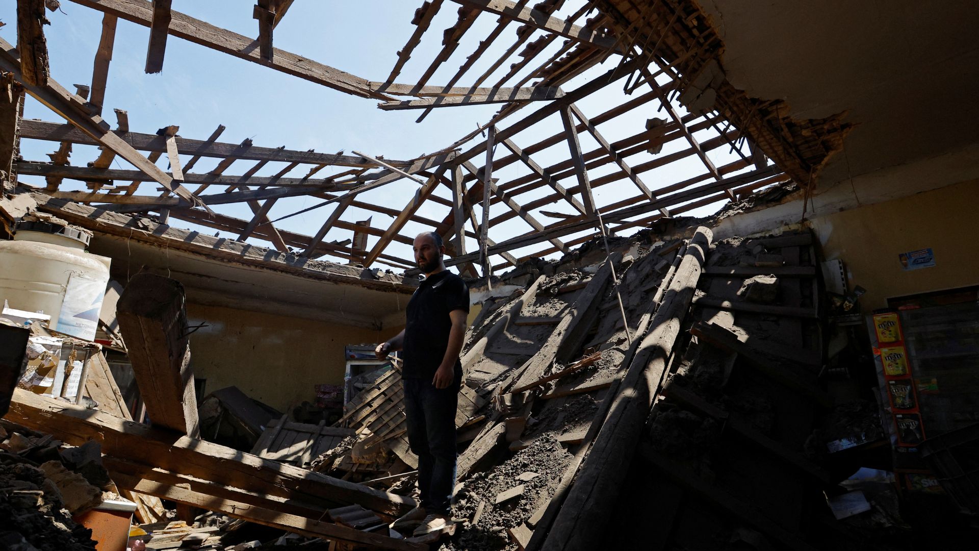 Resident Aran stands inside the shop he rents, destroyed by shelling in Makiivka. /Alexander Ermochenko/Reuters