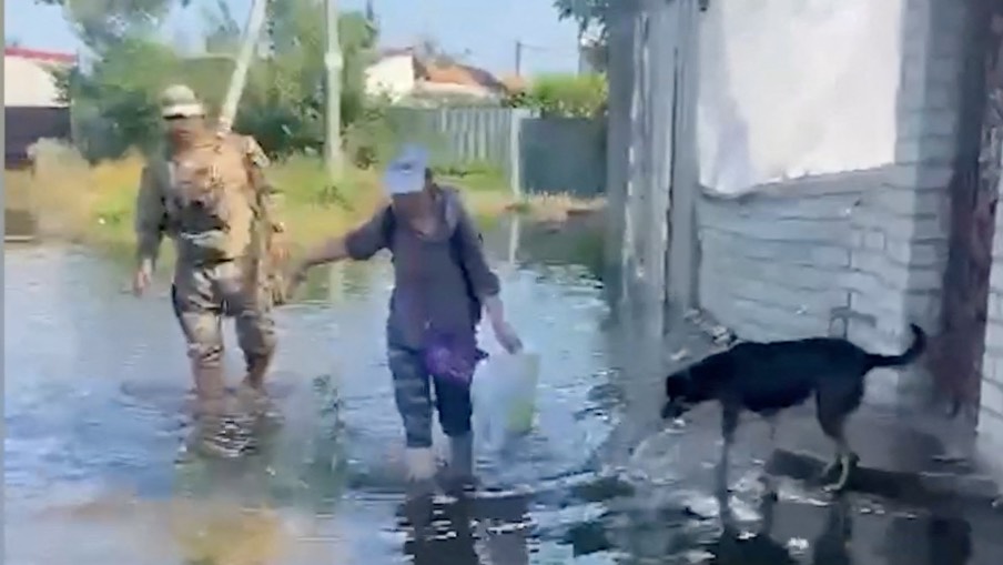 A person wades through floodwaters as police officers, together with rescuers of the State Emergency Service, conduct patrols and help citizens evacuate to safe places, following floods, in Kherson region. /National Police of Ukraine/Reuters