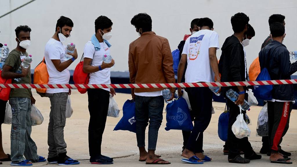 Migrants wait in line prior to board a boat at the port of the the island of Lampedusa, south of Sicily. /Vincenzo Pinto/AFP