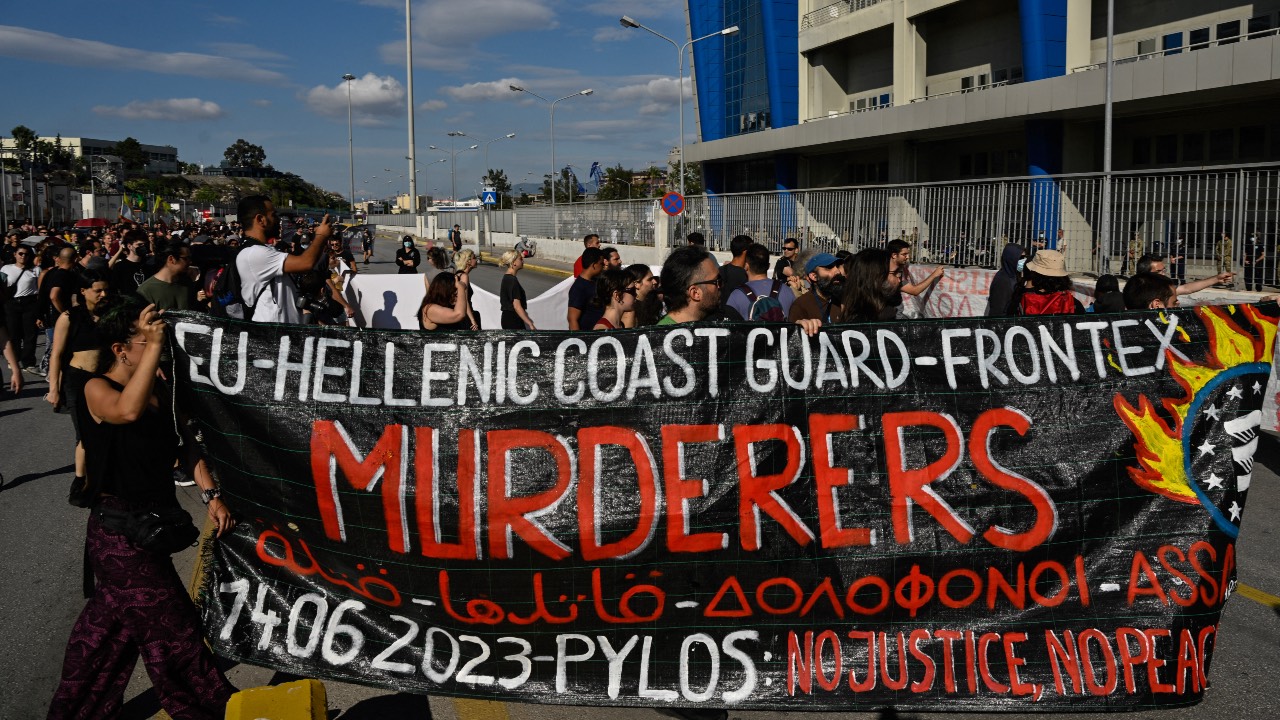 Protesters hold a banner in front of the Frontex and Hellenic Coast Guard headquarters in the port of Piraeus near Athens. /Louisa Gouliamaki/AFP

