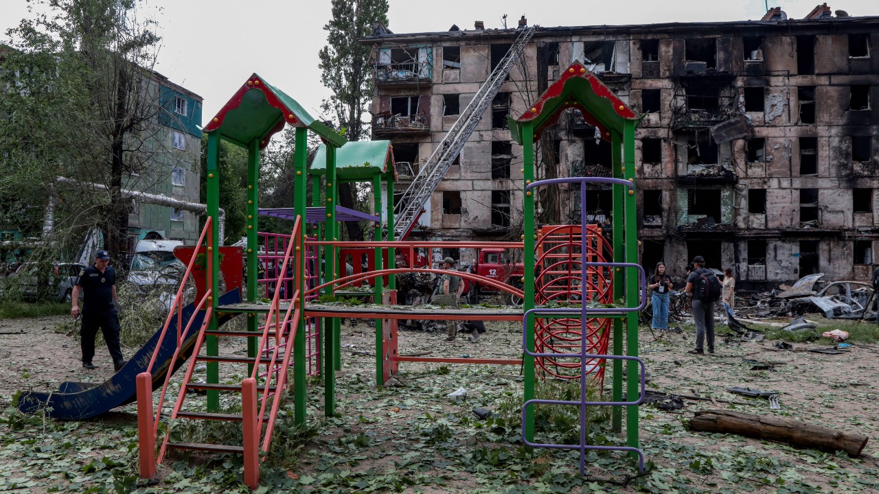 A policeman walks past a children's playground in front of a destroyed residential building in the city of Kryvyi Rig, Ukraine. /Stas Yurchenko/AFP