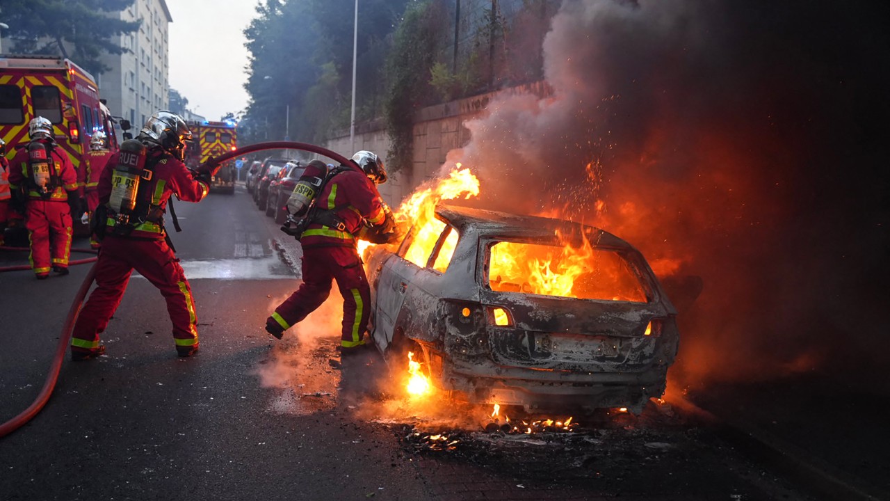 Firefighters douse a burning car in Nanterre, west of Paris, during unrest after a teenager was shot dead. /Zakaria Abdelkafi/AFP