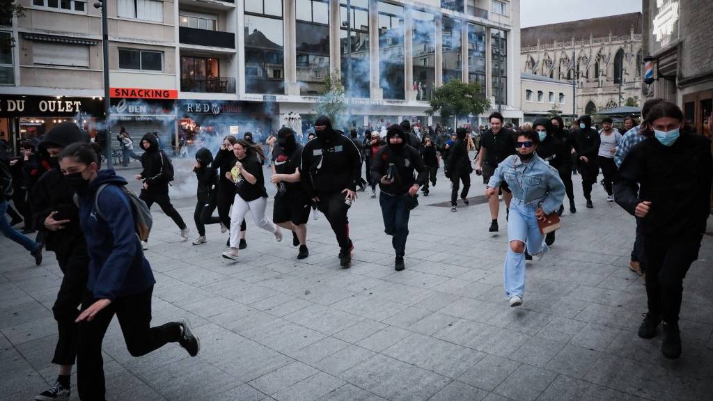 Protesters run from launched tear gas canisters during a demonstration in Caen, north-western France. /Lou Benoist/AFP