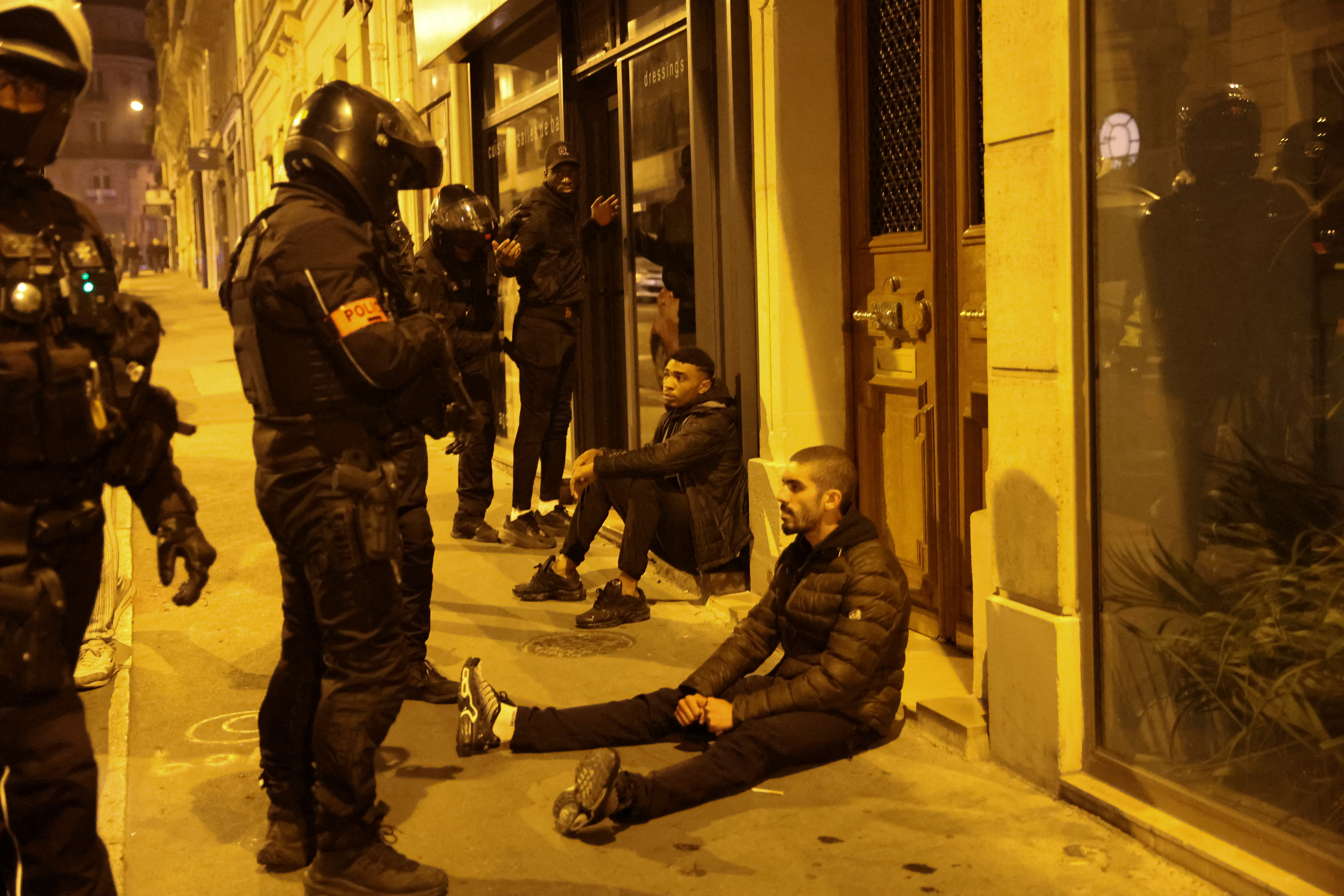 Protesters sit on a sidewalk as police officers stand over them. /Nacho Doce/Reuters