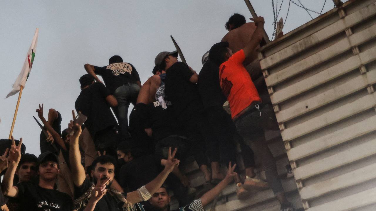 Protesters climb a fence near the Swedish embassy in Baghdad hours after the embassy was stormed and set on fire. /Ahmed Saad/Reuters